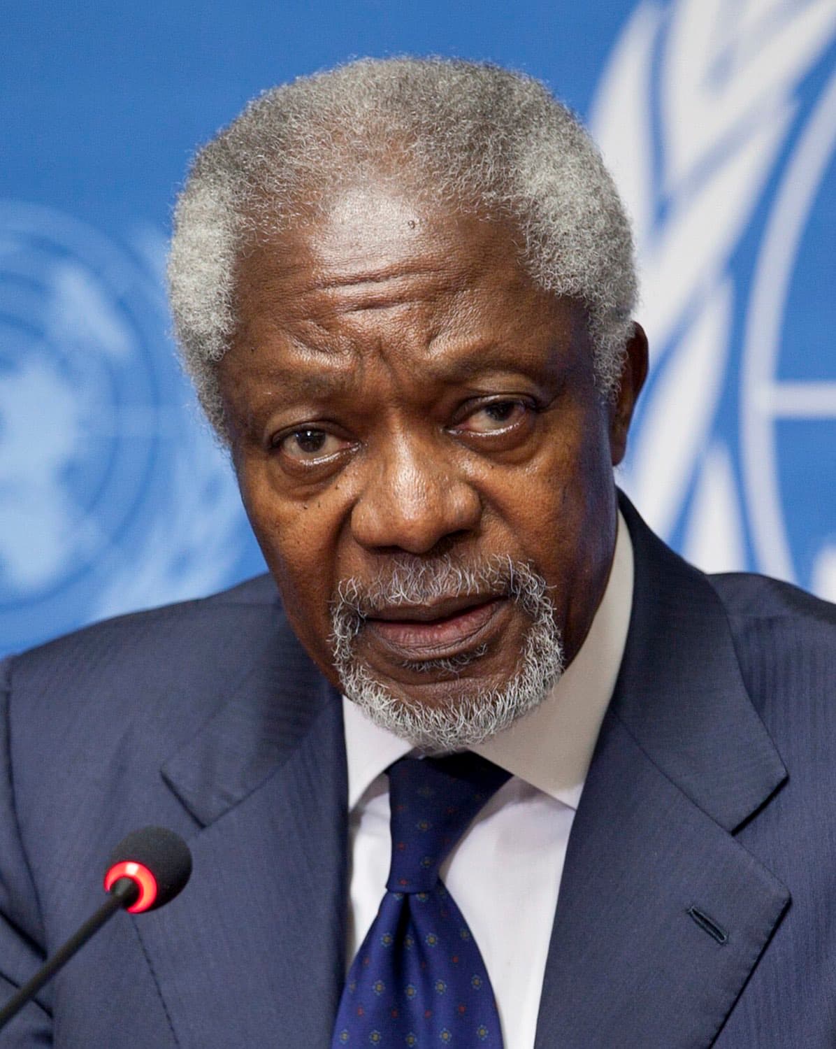 Kofi Annan mit grauem Bart spricht vor dem blauen Emblem der Vereinten Nationen